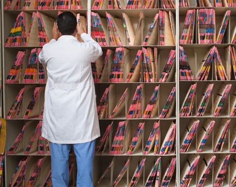 medical professional sorting through shelves of patient files. 