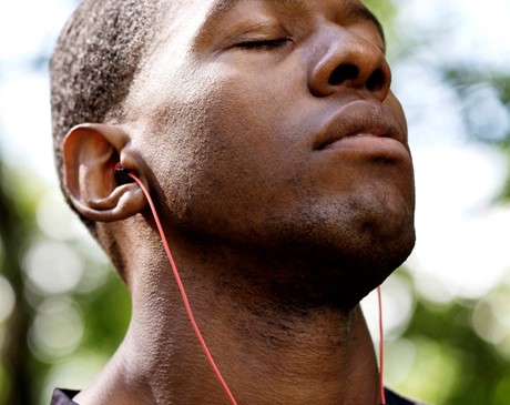 Man with earbuds tilting his head back with eyes closed.