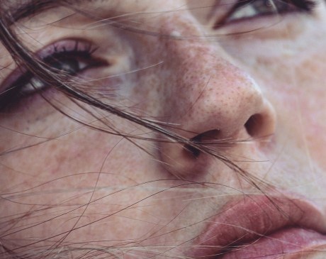 Close-up of woman’s face with strands of hair covering her face.